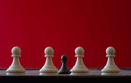 small pawn on chess board against larger adversary concept of adversity, discimination, equality.