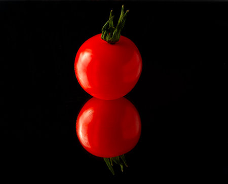 cherry tomato isolated on black background with reflectionの写真素材