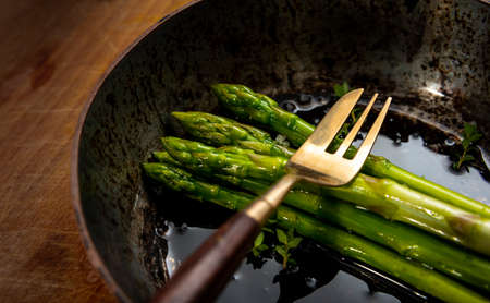 asparagus spears in frying pan on wooden chopping board, good food, healthy eating.の写真素材