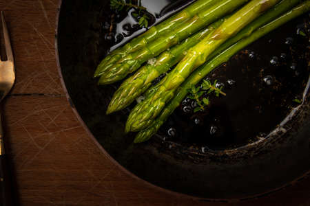 asparagus spears in frying pan on wooden chopping board, good food, healthy eating.の写真素材