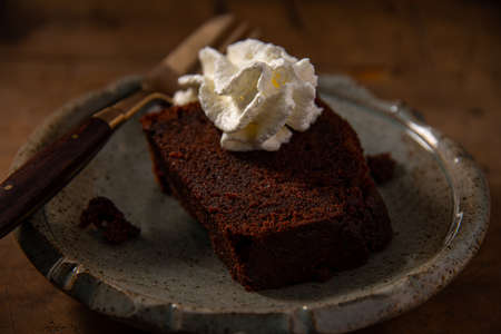 home made chocolate cake or browny with cream on wooden table, unhealthy eating
