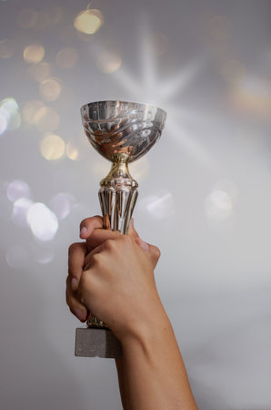 arms holding up cup with bokeh background, concept of winning and success.の写真素材