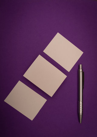 three blank business cards and a pen on purple background, mock up branding.の写真素材