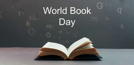 world book day ,open book with letters spilling out on a gray background with the text world book day .の写真素材