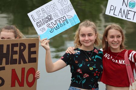 Gold Coast May 03 2019: School students at Climate election day of action> Signs read learn to change or learn to swim , no planet. 3 signs and 3 female students holding protest signs next to water at Gold coast on sunny dayのeditorial素材