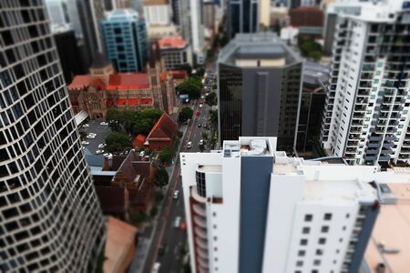 Elevted view of city with church and buildings in minature effect. Main roda with cars lined by trees. Tall buildings office and residental apartments surround the church and road.の写真素材