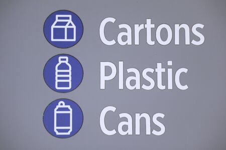 Blue and white sign with bold text. Cartons, plastic and cans with sumbolds of each