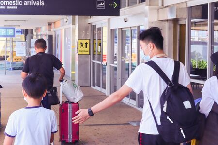 Gold Coast, Australia January 30 2020: Asian family at Gold Coast airport with masks on and luggage Queensland.のeditorial素材