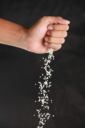 gesture of hands were dropped rice down in the black backgroundの写真素材