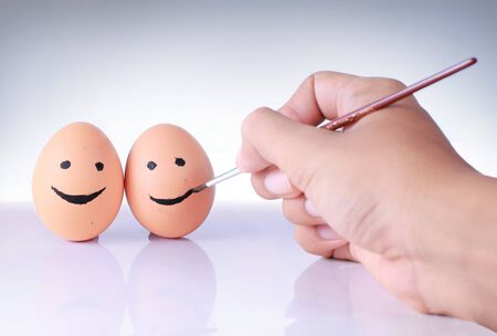 hands drawing smiley face on eggの写真素材
