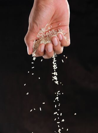 gesture of hands were dropped rice down in the black backgroundの写真素材