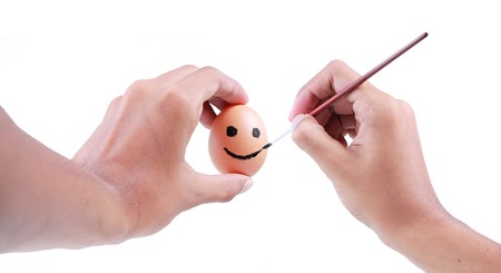 hands drawing smiling face on eggの写真素材