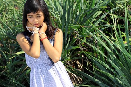 Young asian woman thinking about something outdoorの写真素材