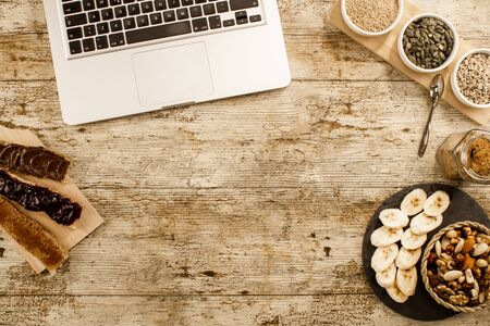 Wooden table set for a sweet vegan breakfast shot from above with sliced banana, mixed dried fruit,...