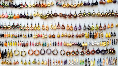 Concept: the value of craftsmanship. Many handmade colored wooden earrings displayed in a row for saleの写真素材
