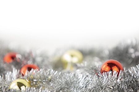 Christmas copy space with red and gold bright baubles in silver decorative chain on bottom on white background and bokeh effectの写真素材