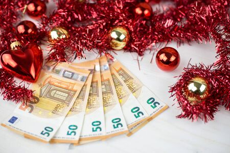 Christmas money business concept: some fifty euro banknotes with red and gold baubles and wreath...
