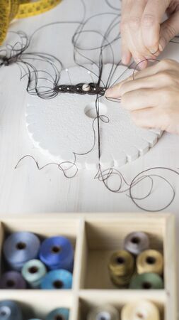 Lifestyle concept, work from home to reinvent your life: close-up of woman hands making macrame...