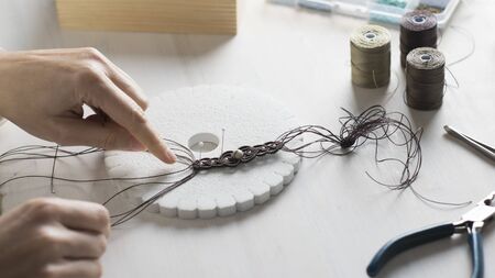 Lifestyle concept, work from home to reinvent your life: close-up of woman hands making macrame...