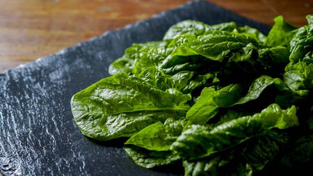 Healthy vegan food concept: close-up backlight of freshly picked green spinach leaves placed on a...