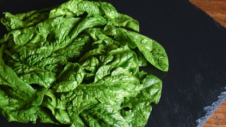 Healthy vegan food concept: close-up backlight of freshly picked green spinach leaves placed on a...