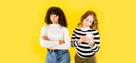 Two mixed race young women isolated funny picture on yellow background for copy space - Caucasian...