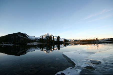 The begining of a lake freezing over as winter approaches.の写真素材