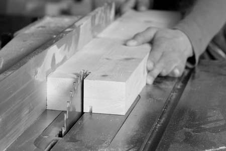 A black and white photo of a board being ripped on a tablesaw.の写真素材
