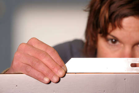 A woodworker checks her work with a square.  Shallow depth of field, focus on her hands.の写真素材