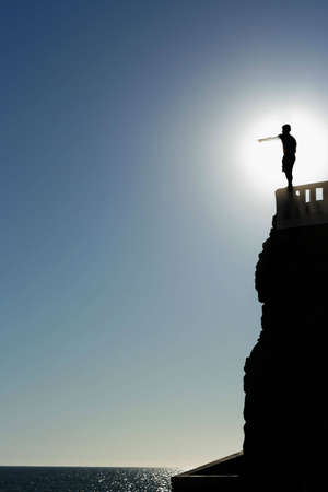A cliff diver in Mexico points to the ocean that he is about to leap into.の写真素材