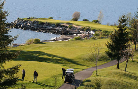 A golfing trio sizes up the distance to the green at the edge of Howe Sound, British Columbia.の写真素材