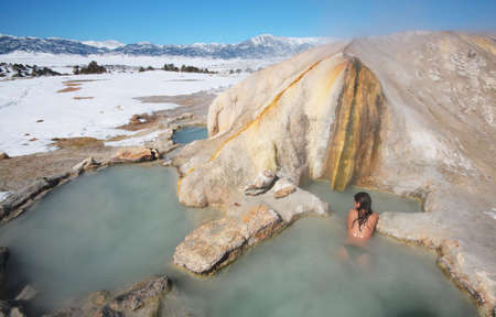 A girl relaxes in the pool of a natural hot spring.の写真素材