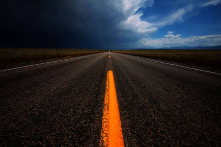 A straight road leading into changing weather.  の写真素材