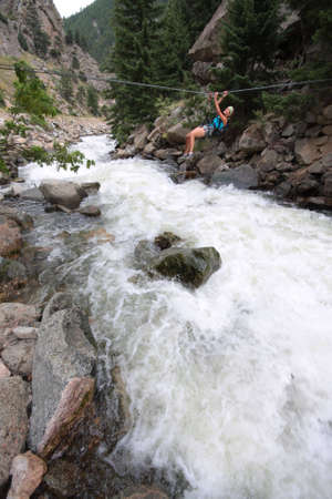 A girl crosses a creek via a tyrolean traverse.の写真素材