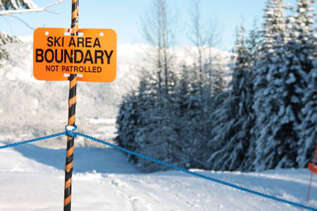 A sign warns skiers and snowboarders that the are they are about to enter is out of bounds and not patrolled.の写真素材