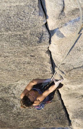 A fit and attractive girl climbs a granite rock in Squamish British Columbia Canada.