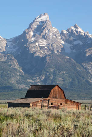 A weathered barn sits against the backdrop of the Grand Tetons in Wyomingの写真素材