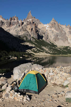 A tent set up on the edge of a pristine alpine lake.の写真素材