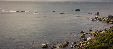A group of ocean kayak paddlers on their surfskis move over calm water through the rocksの写真素材