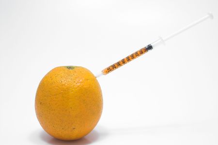 An orange being injected with juice from a syringe.の写真素材