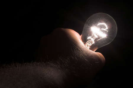 A person powering a light bulb by holding it.の写真素材