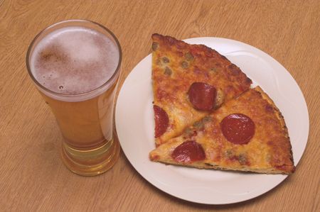 A slice of pizza and a beer in a pilsner glass.の写真素材