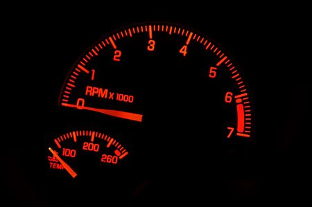 A red tachometer and temperature gauge on an automobile dashboard.