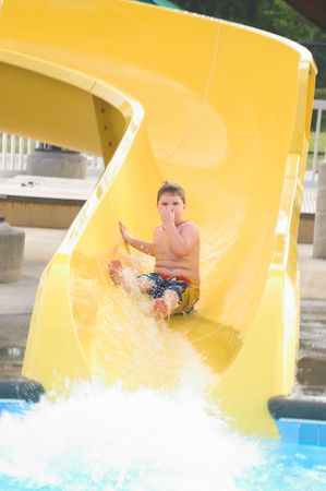 A young boy sliding down a water slide.