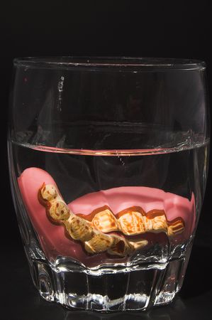 A set of stained false teeth in a cleaning solution.の写真素材