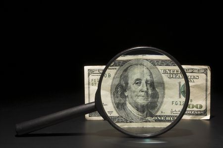 A 100 dollar bill under a magnifying glass.の写真素材