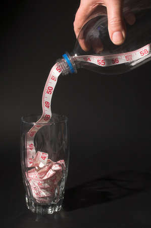 Weight Loss Concept - A tailor's tape pouring into a drinking glass.の写真素材