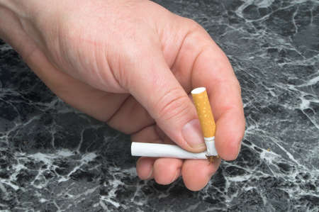 A person breaking a cigarette, signifying that they are quitting smoking.