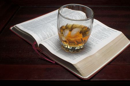A glass of bourbon on the rocks next to a bible.の写真素材