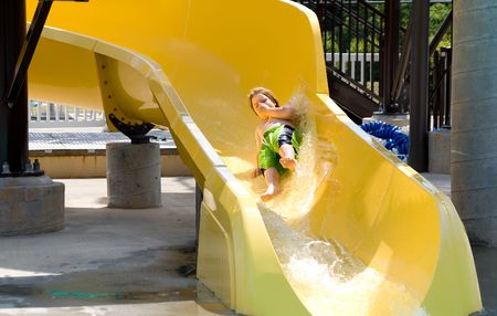 A young boy sliding down a water slide.